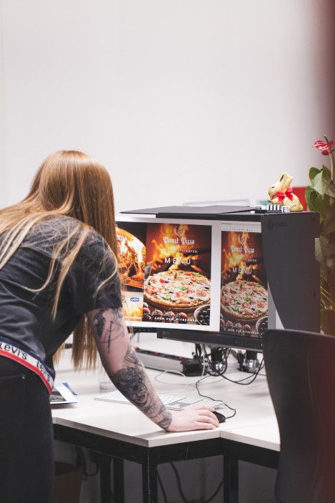 Druckvorstufenmitarbeiterin beim Vergleichen eines Ausdruckes gegenüber einem kalibrierten Bildschirm Druckvorstufenmitarbeiterin beim Vergleichen eines Ausdruckes gegenüber einem kalibrierten Bildschirm