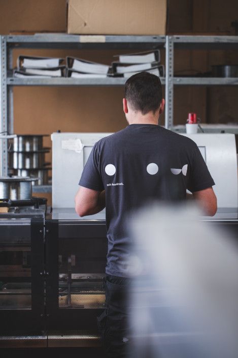 Mitarbeiter in der Endfertigung vor dem Sammelhefter Mitarbeiter in der Endfertigung vor dem Sammelhefter