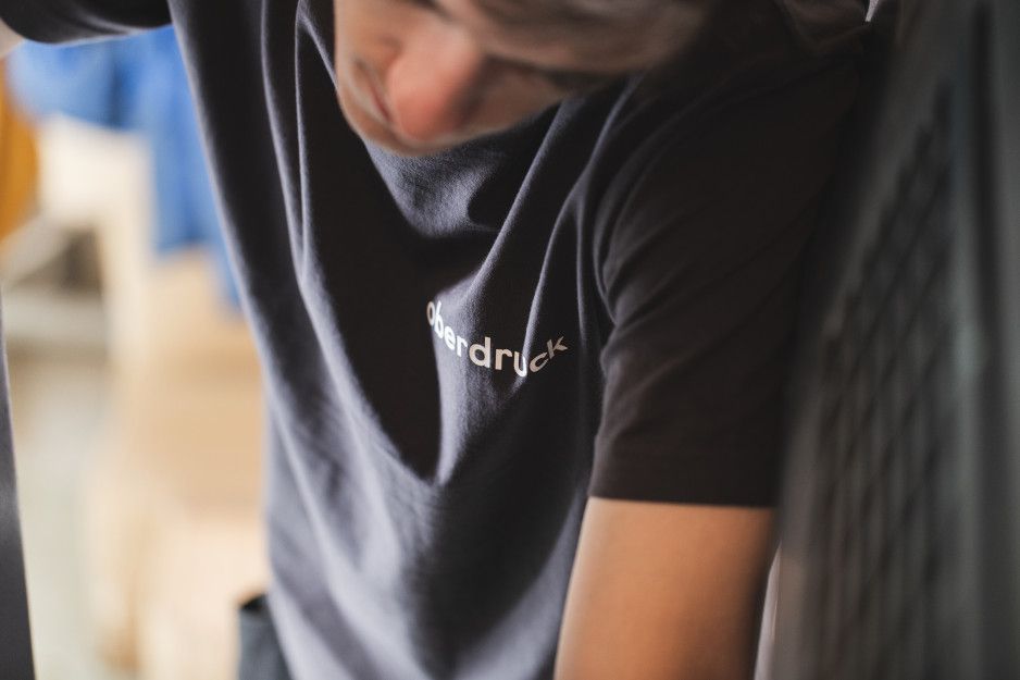 Detailaufnahme von Bogenflachdrucker mit Oberdruck T-Shirt Detailaufnahme von Bogenflachdrucker mit Oberdruck T-Shirt